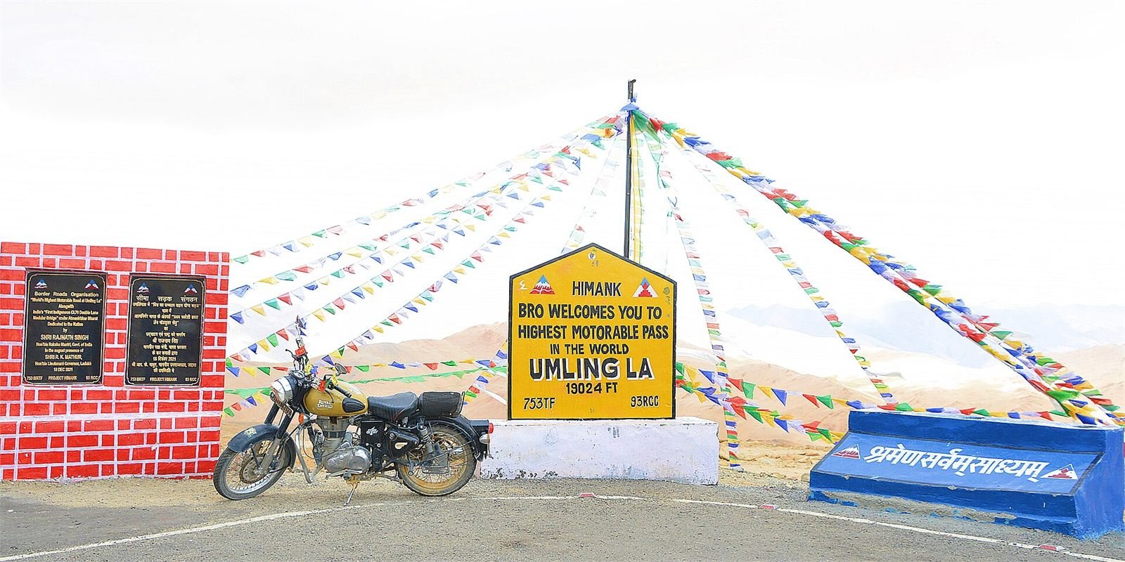 A Royal Enfield motorcycle parked beside the Umling La summit sign, the world's highest motorable pass