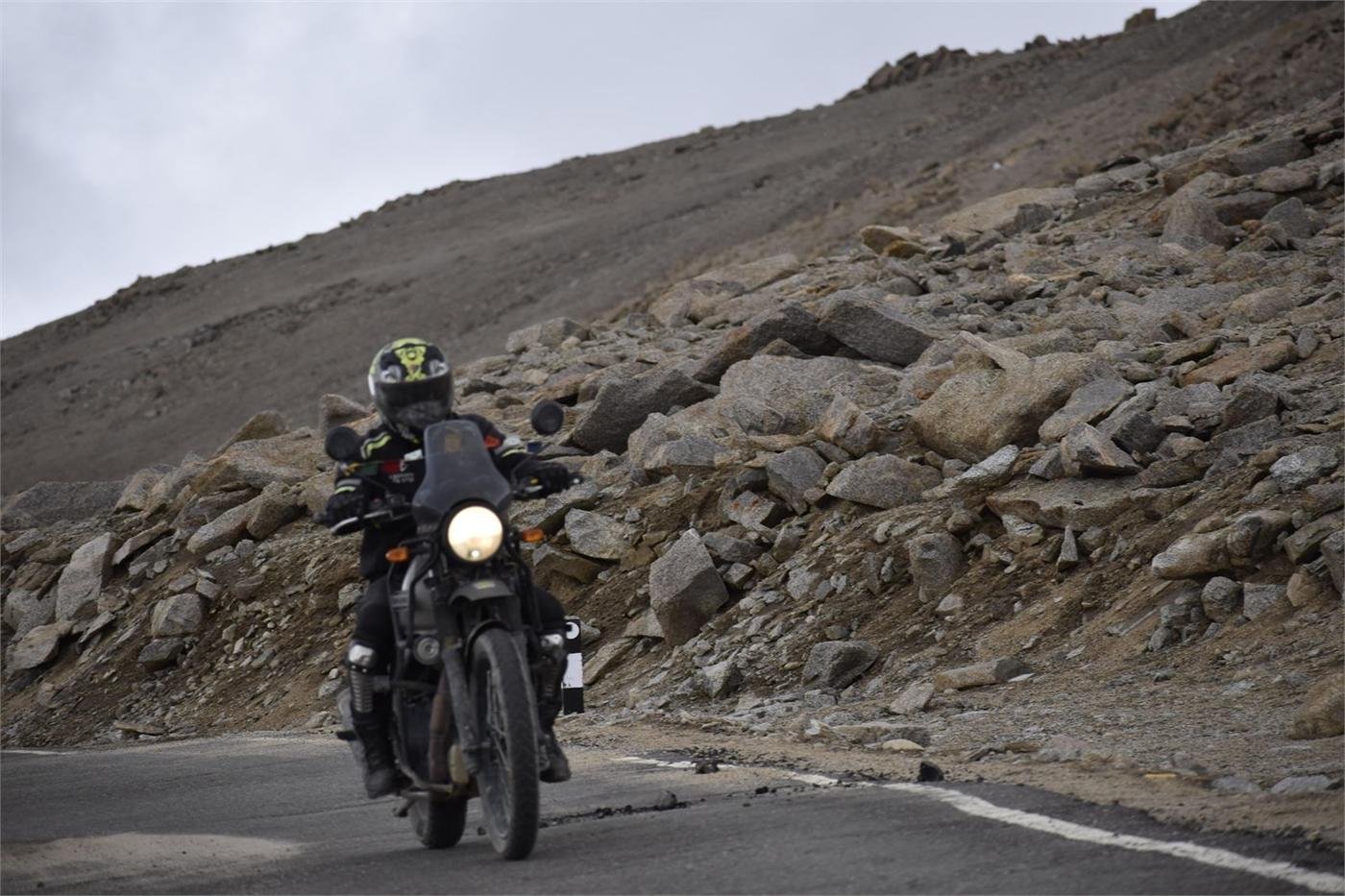 A rider on a Royal Enfield climbing a rocky switchback mountain road