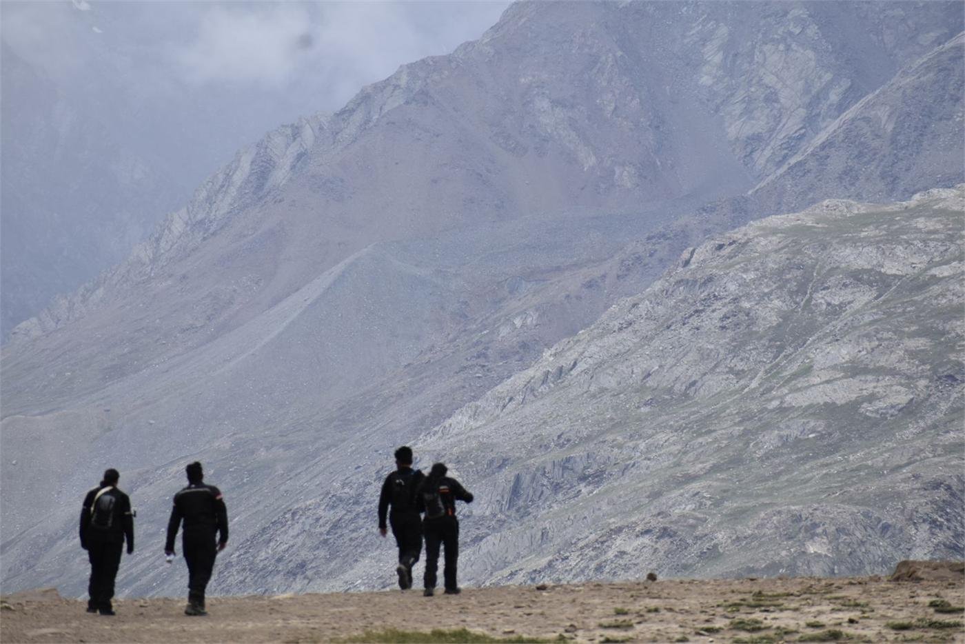 Three silhouetted riders walking a high mountain trail