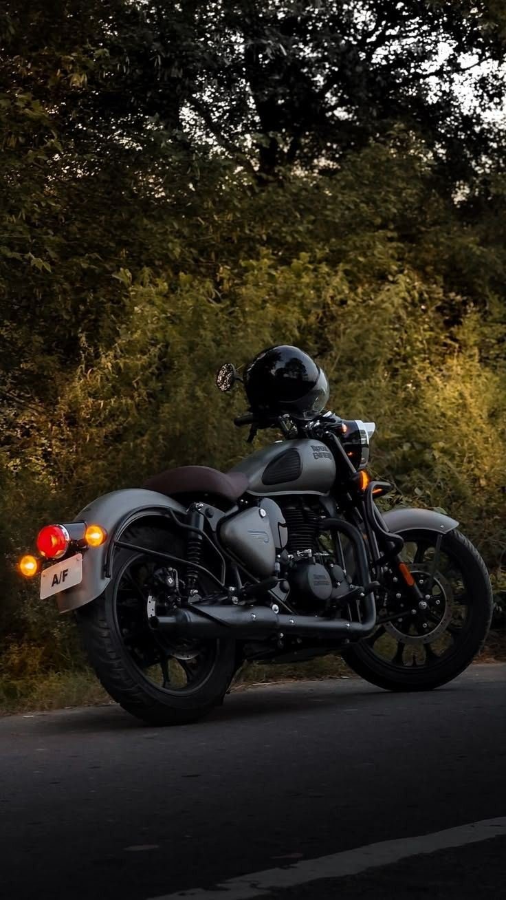 A Royal Enfield roadster on a tree-lined road at dusk